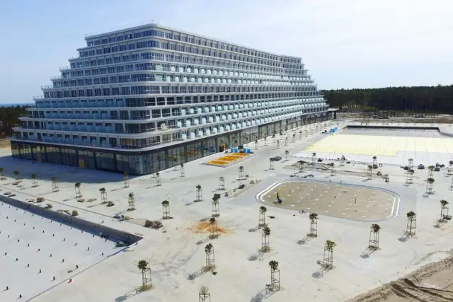 Hotel Gołębiewski Pobierowo kiedy otwarcie? Nowoczesny hotel w kształcie piramidy, wciąż w budowie, z basenami i terenami zielonymi.