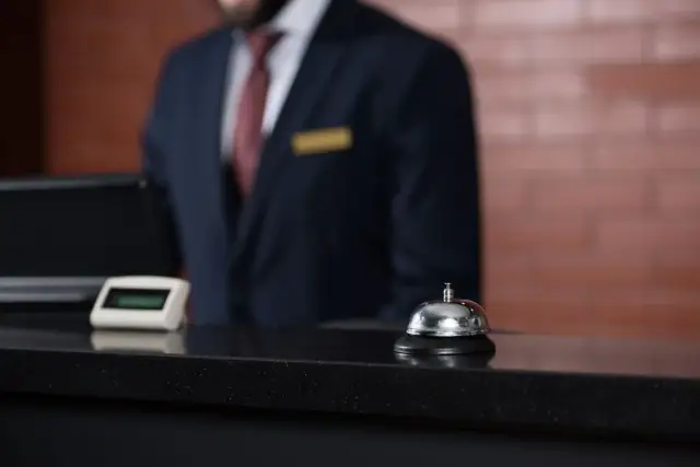 Recepcjonista w hotelu, dzwonek i komputer. Zastanawiasz się, ile zarabia recepcjonistka w hotelu?